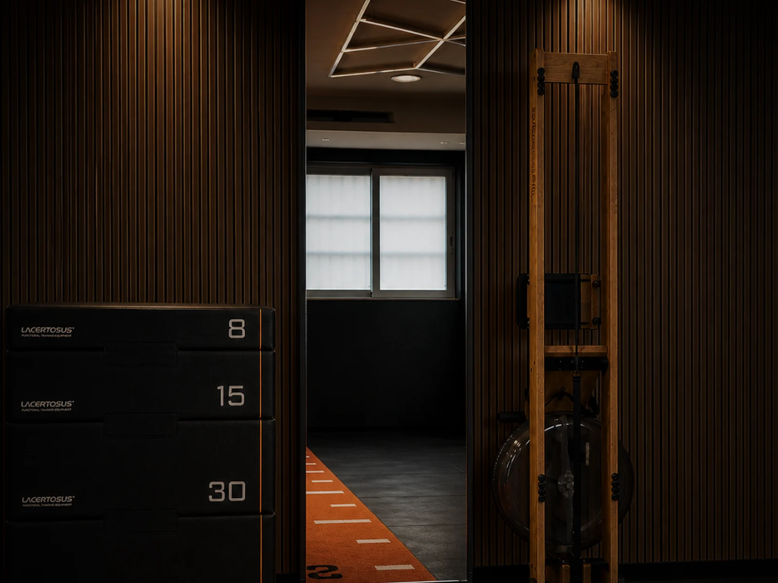 Sala training AMW con boiserie in legno, pedana e attrezzature Lacertosus